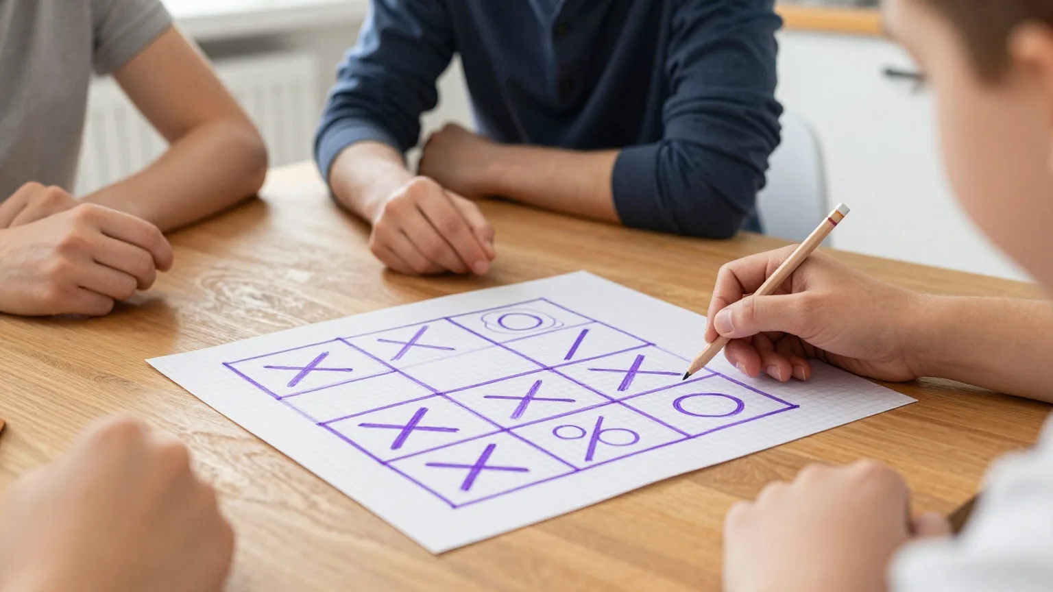 Kariertes Papier auf einem Küchentisch mit einem gezeichneten Neunerfeld voller Kreuze und Kreise, daneben ein Bleistift